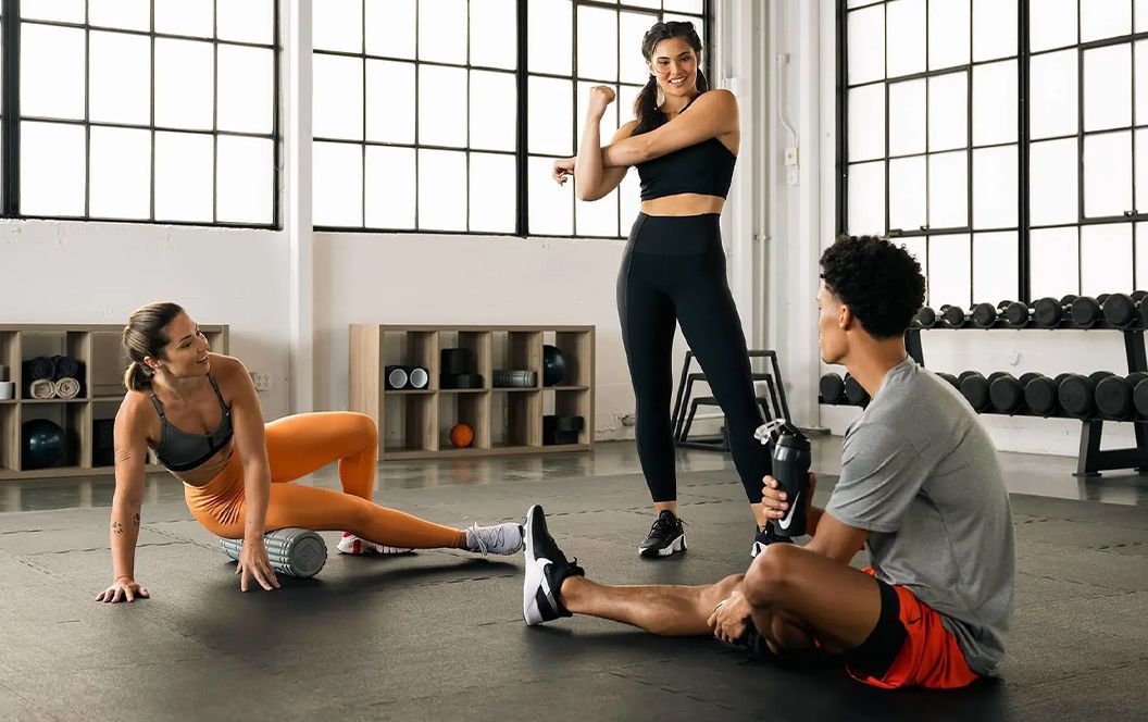 Trois sportifs qui s'étirent dans une salle de sport