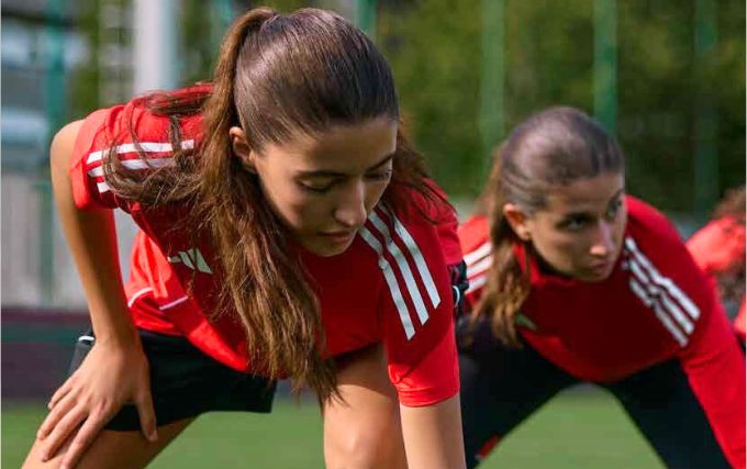 Joueuses avec des ensembles adidas rouge et noir qui s'échauffent