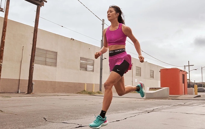 Femme habillée avec des vêtements Nike rose et qui court